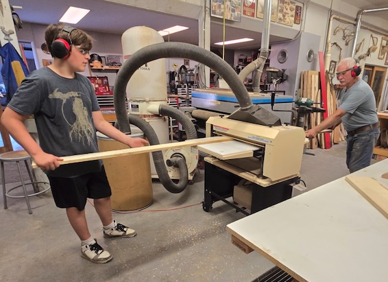 Tim Heming and his grandson, Connor, run a workpiece through Tim's Woodmaster Planer.